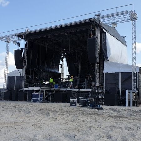 Eine Bühne am Strand mit einem großen Bildschirm im Hintergrund, bereit für eine Veranstaltung im Freien.