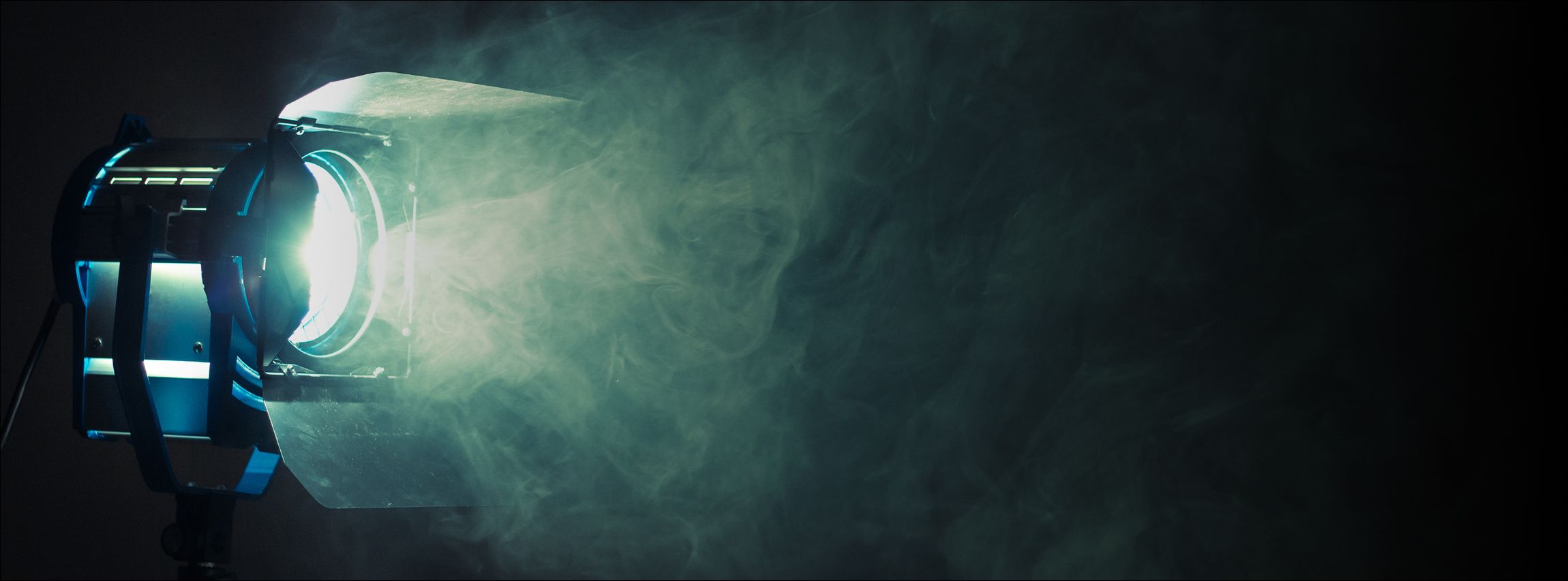 Hintergrundbild - ein Bühnenscheinwerfer leuchtet und macht Effektnebel dramatisch sichtbar.